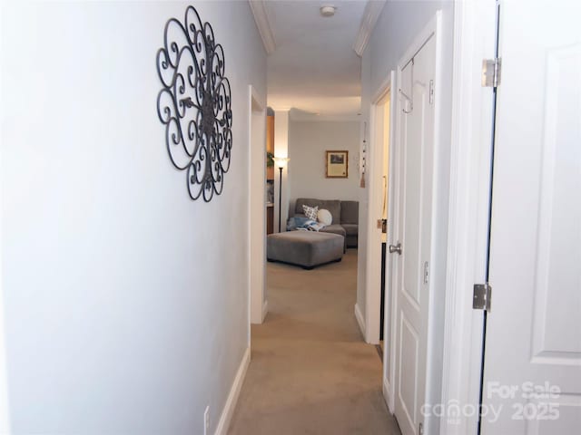 hall featuring light carpet, crown molding, and baseboards