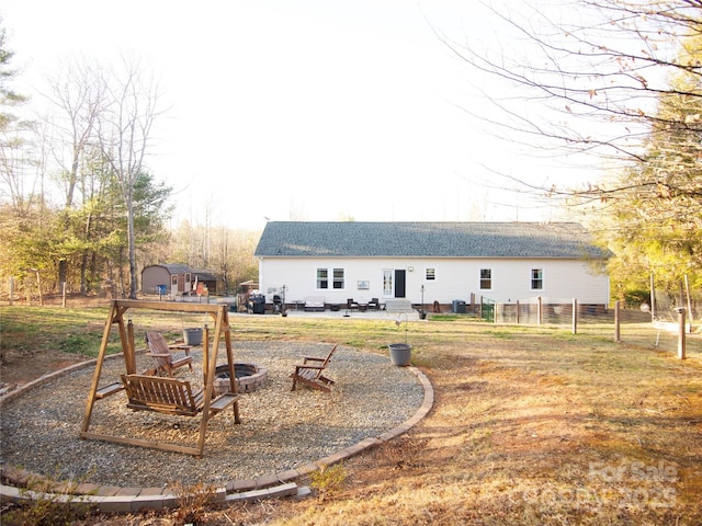 rear view of house with a fire pit and fence