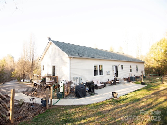 rear view of property with fence, central AC unit, a lawn, and a gate