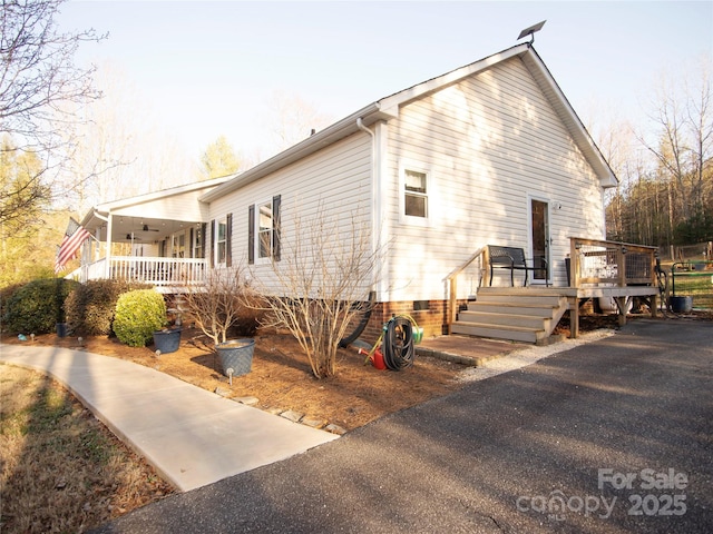 view of side of property with a ceiling fan and a wooden deck