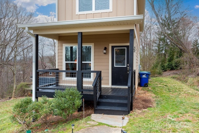 view of exterior entry with covered porch and board and batten siding