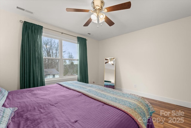 bedroom with visible vents, baseboards, wood finished floors, and a ceiling fan