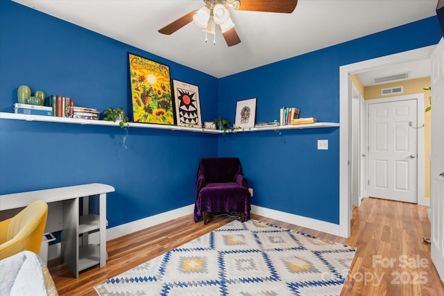 sitting room with visible vents, ceiling fan, baseboards, and wood finished floors