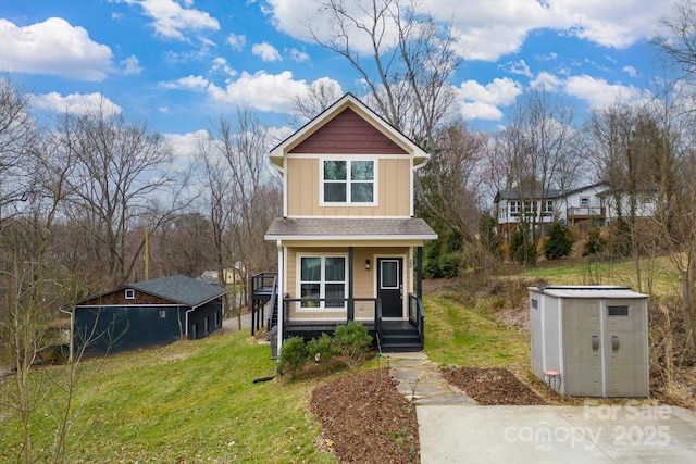 view of front of property featuring a porch, an outbuilding, board and batten siding, and a front lawn