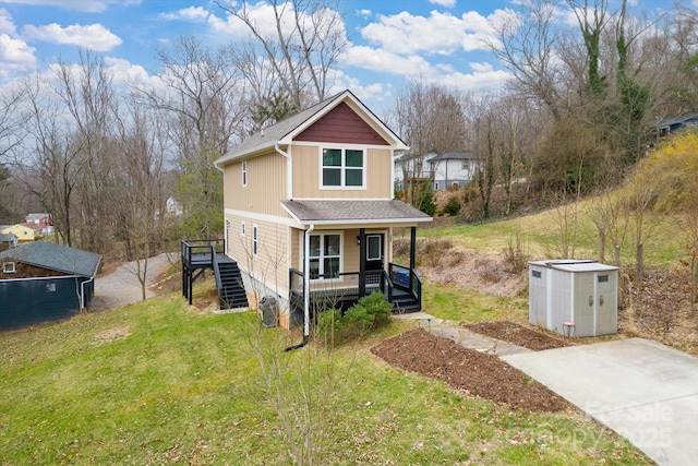 view of home's exterior with a porch, stairs, an outdoor structure, a lawn, and board and batten siding