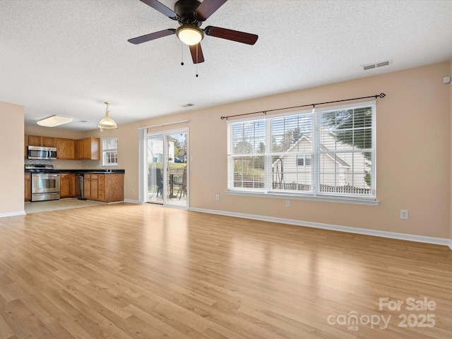 unfurnished living room with visible vents, light wood-style floors, and a textured ceiling