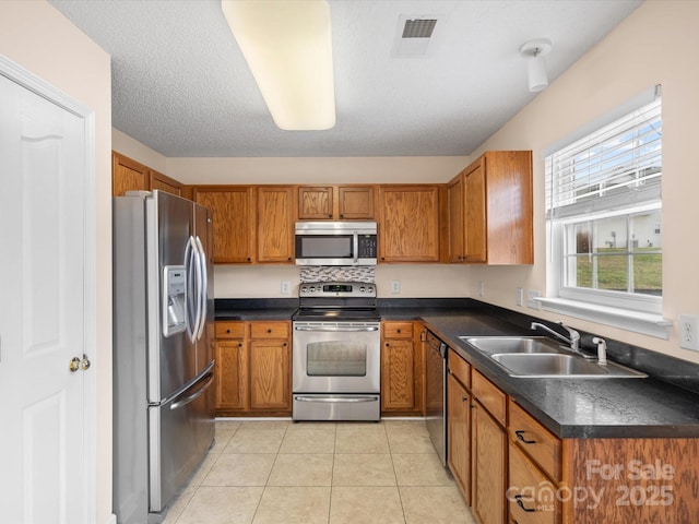 kitchen featuring a sink, stainless steel appliances, visible vents, and brown cabinetry