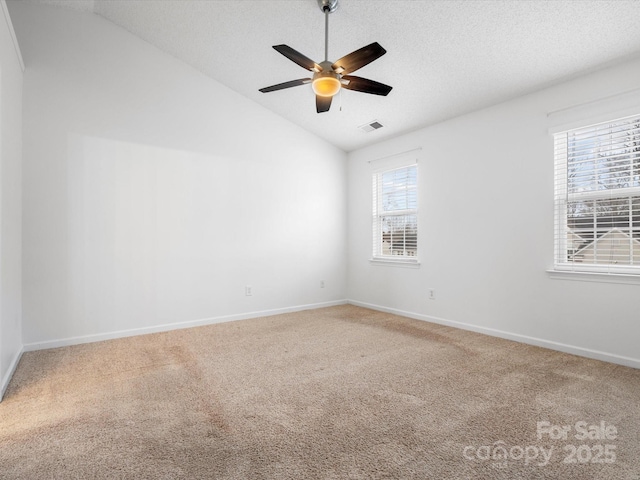 carpeted spare room featuring baseboards, a textured ceiling, a ceiling fan, and vaulted ceiling