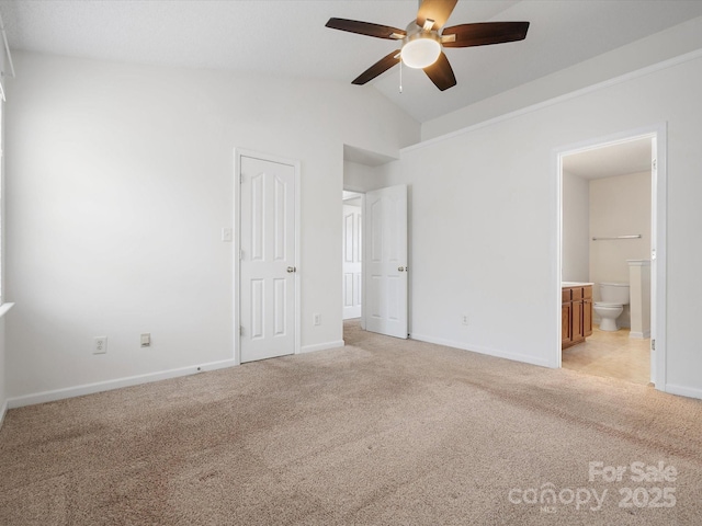 unfurnished bedroom with baseboards, light colored carpet, ensuite bath, and lofted ceiling