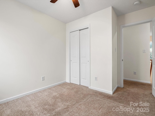 unfurnished bedroom featuring a closet, baseboards, a ceiling fan, and carpet flooring