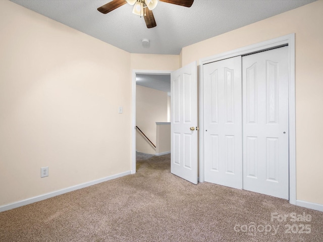 unfurnished bedroom featuring a closet, baseboards, a textured ceiling, and carpet