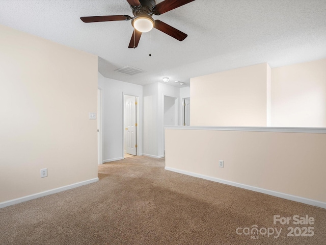 carpeted spare room with visible vents, a textured ceiling, and baseboards