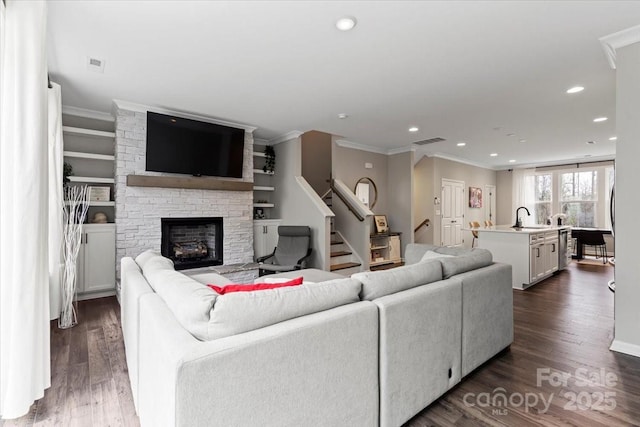 living area with dark wood finished floors, visible vents, and ornamental molding