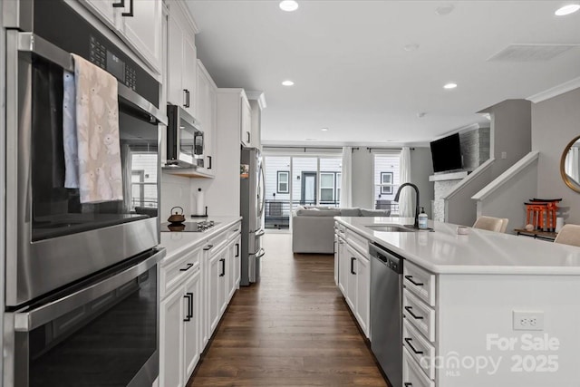 kitchen featuring dark wood finished floors, open floor plan, light countertops, stainless steel appliances, and a sink