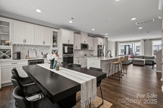 dining space featuring beverage cooler, visible vents, recessed lighting, ornamental molding, and dark wood-type flooring