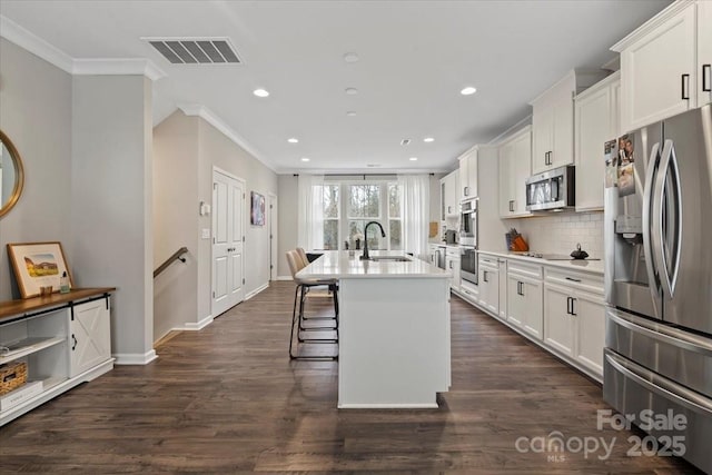 kitchen with visible vents, stainless steel appliances, crown molding, and a sink