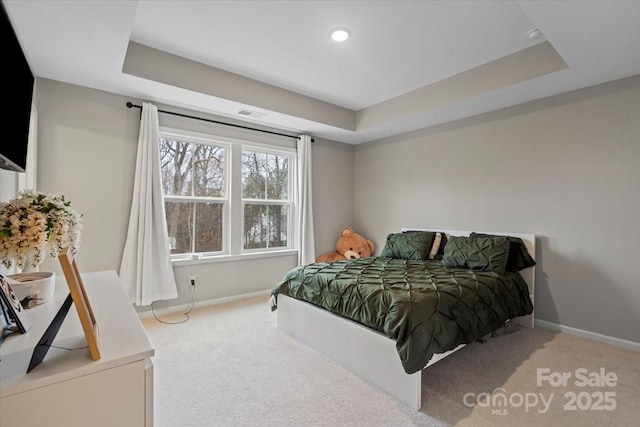 bedroom with a tray ceiling, carpet floors, and baseboards