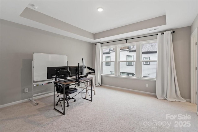 carpeted office space featuring visible vents, baseboards, and a tray ceiling