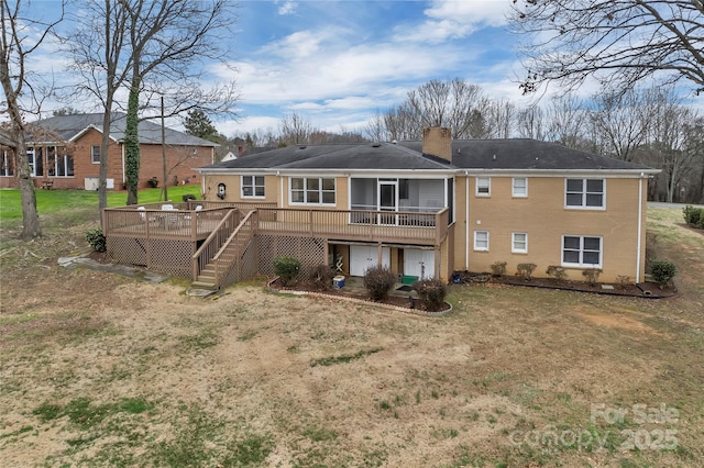 back of house featuring a wooden deck, a yard, a chimney, stairs, and brick siding