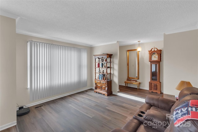 living area featuring visible vents, a textured ceiling, crown molding, and wood finished floors