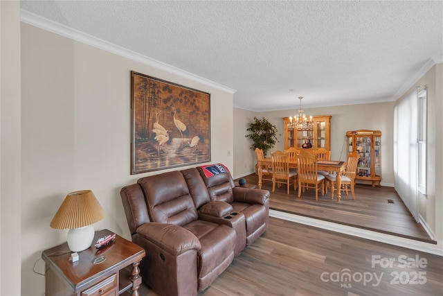 living area featuring a chandelier, a textured ceiling, crown molding, and wood finished floors