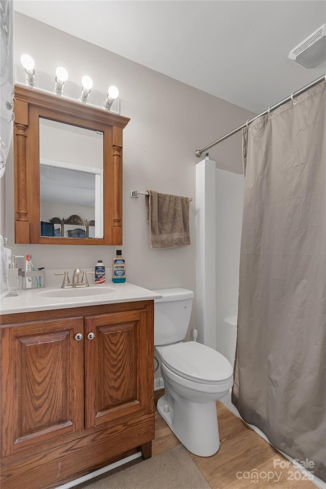 full bathroom with visible vents, toilet, wood finished floors, a shower with shower curtain, and vanity