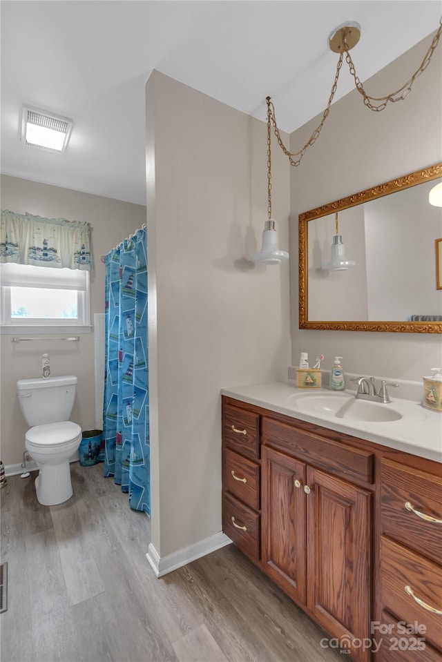 bathroom with baseboards, toilet, wood finished floors, and vanity