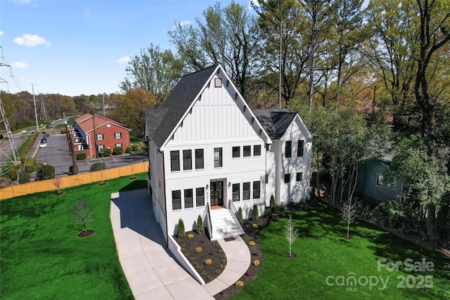view of front facade with board and batten siding, stucco siding, fence, and a front yard