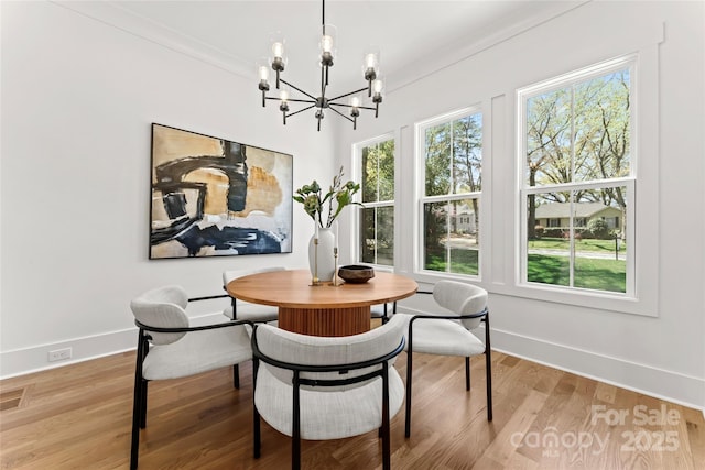 dining area featuring baseboards, light wood finished floors, and a chandelier