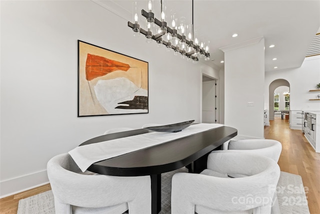 dining space featuring arched walkways, baseboards, light wood finished floors, and recessed lighting
