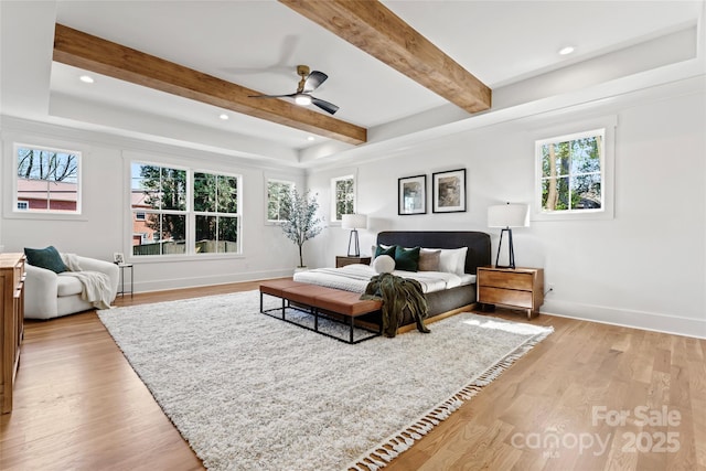 bedroom with multiple windows, light wood-style floors, baseboards, and beamed ceiling