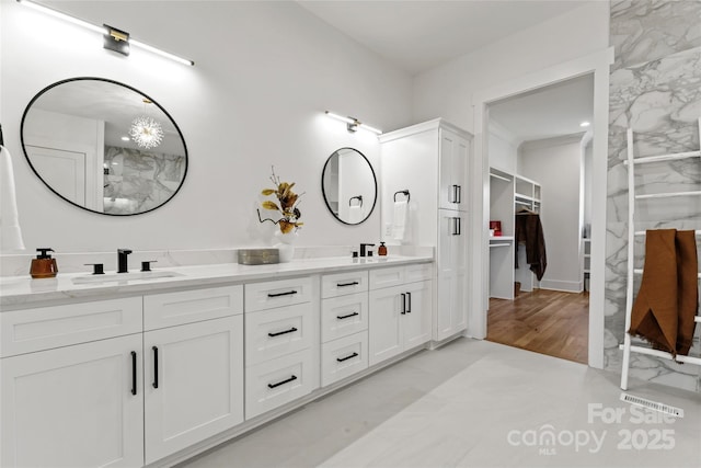 full bathroom with double vanity, a walk in closet, and a sink