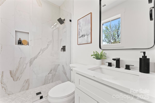 bathroom featuring toilet, vanity, visible vents, and a marble finish shower