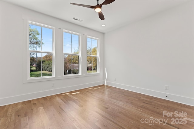 spare room with wood finished floors, visible vents, baseboards, and a ceiling fan