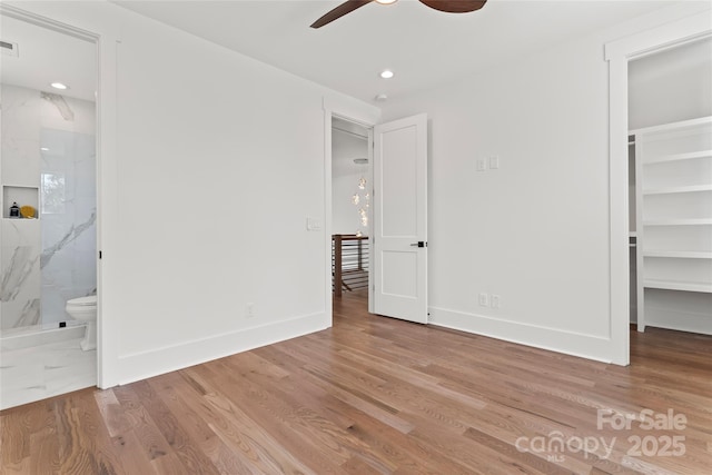 unfurnished bedroom with connected bathroom, wood finished floors, a walk in closet, visible vents, and recessed lighting