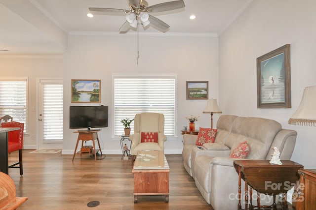 living room featuring baseboards, crown molding, ceiling fan, and wood finished floors