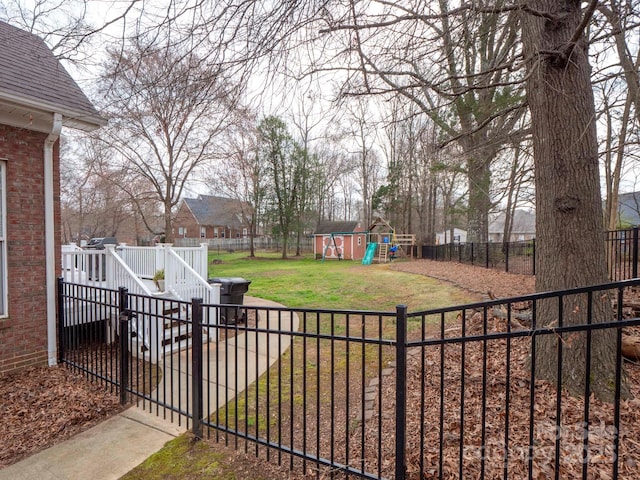 view of yard featuring a deck, a playground, and a fenced backyard