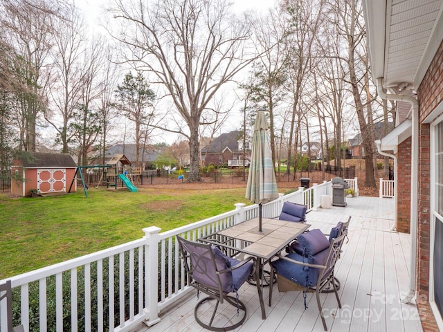 wooden terrace featuring a shed, a yard, a fenced backyard, an outdoor structure, and a playground