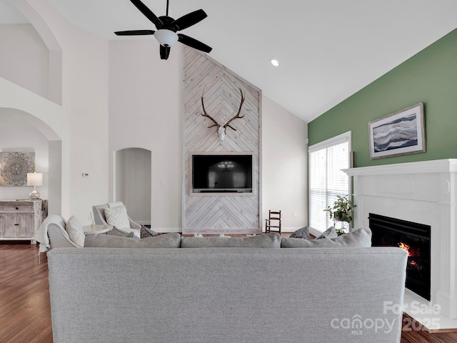 living room with a tiled fireplace, dark wood finished floors, recessed lighting, high vaulted ceiling, and a ceiling fan