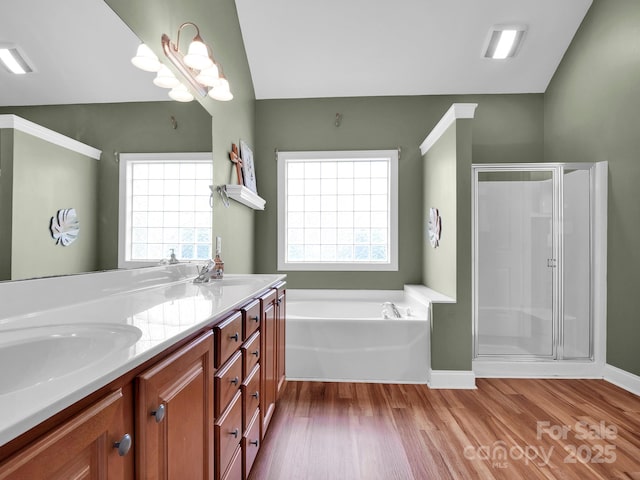 full bath featuring a shower stall, double vanity, wood finished floors, a bath, and a sink