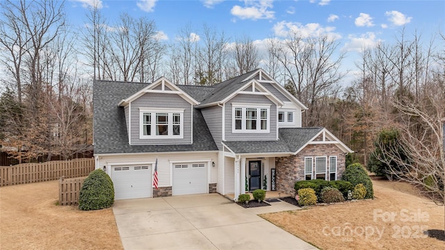 craftsman house with stone siding, driveway, a garage, and fence