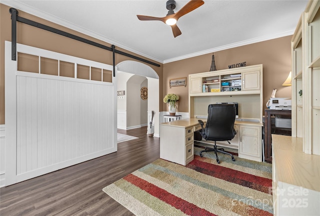 home office featuring a ceiling fan, wood finished floors, arched walkways, and ornamental molding