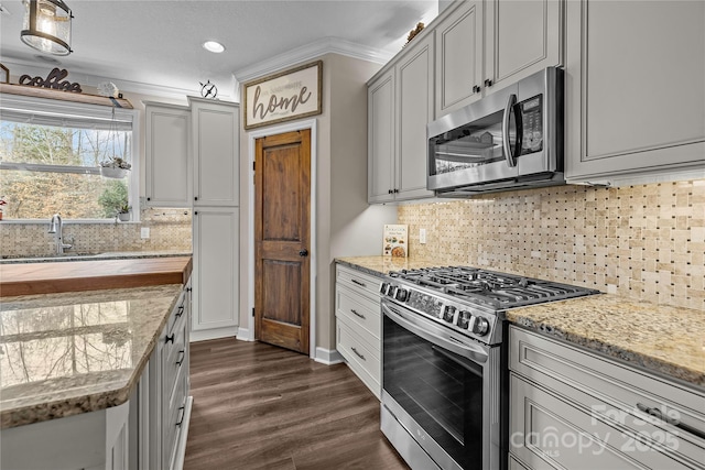 kitchen with a sink, gray cabinetry, crown molding, stainless steel appliances, and dark wood-style flooring