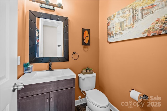 bathroom with baseboards, toilet, and vanity