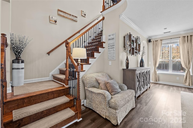 staircase with visible vents, crown molding, baseboards, and wood finished floors