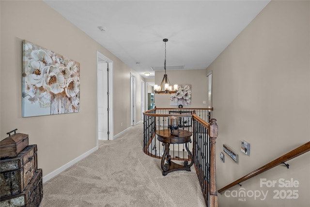 hallway with visible vents, baseboards, carpet floors, a notable chandelier, and an upstairs landing