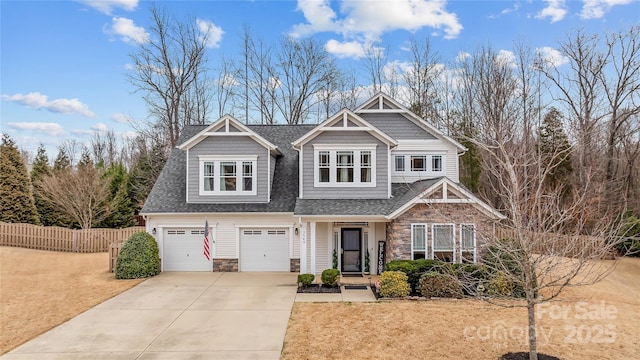 craftsman-style home featuring a shingled roof, fence, concrete driveway, a garage, and stone siding