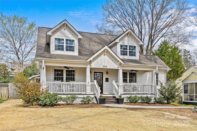 view of front of home with board and batten siding, a front yard, covered porch, and ceiling fan