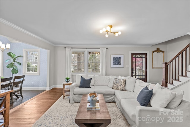 living area with stairway, wallpapered walls, an inviting chandelier, and wood finished floors