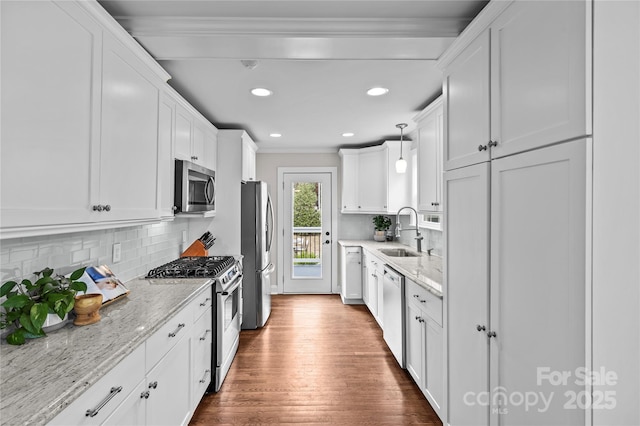 kitchen with dark wood finished floors, a sink, white cabinets, appliances with stainless steel finishes, and crown molding